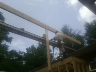 Carpenter setting a ridge beam over a new addition frame — Ice Dam Removal by Roofing Brothers in Lusk