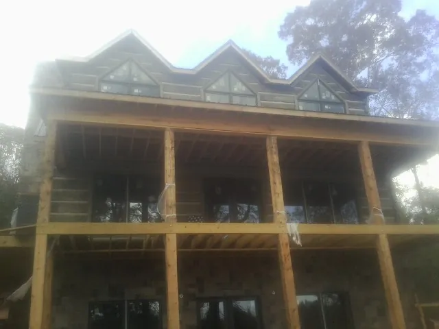 Dormers and porch framing on a large log home under construction — Roof Coating work by our crew in Lusk