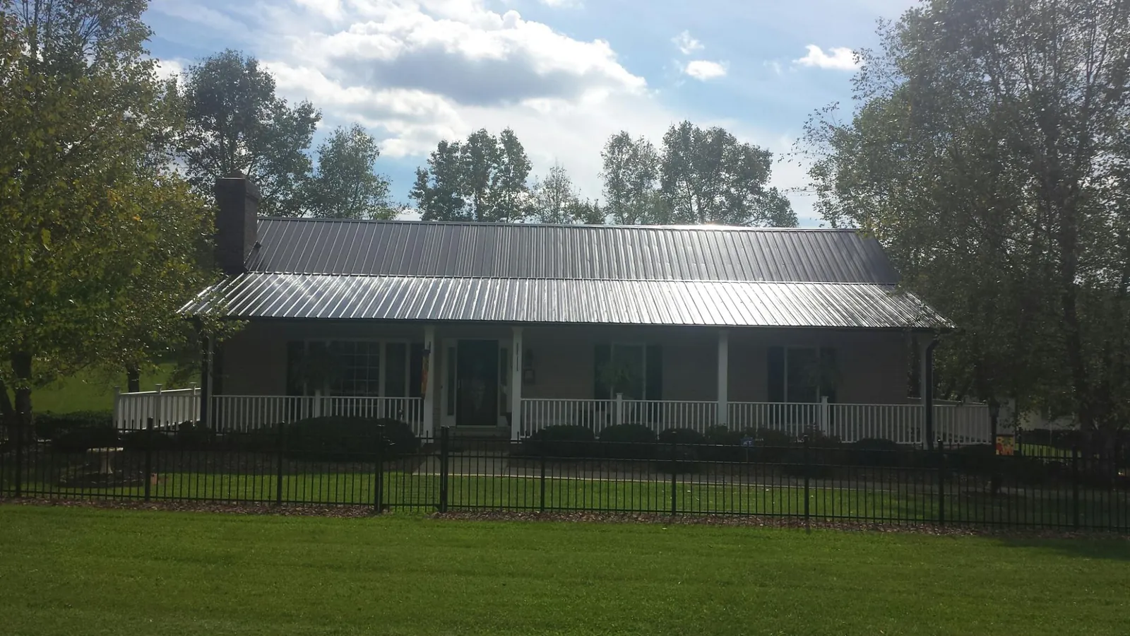 Gray metal roof on a brick ranch with a full width front porch — Gutter Guard Installation work by our crew in Lusk