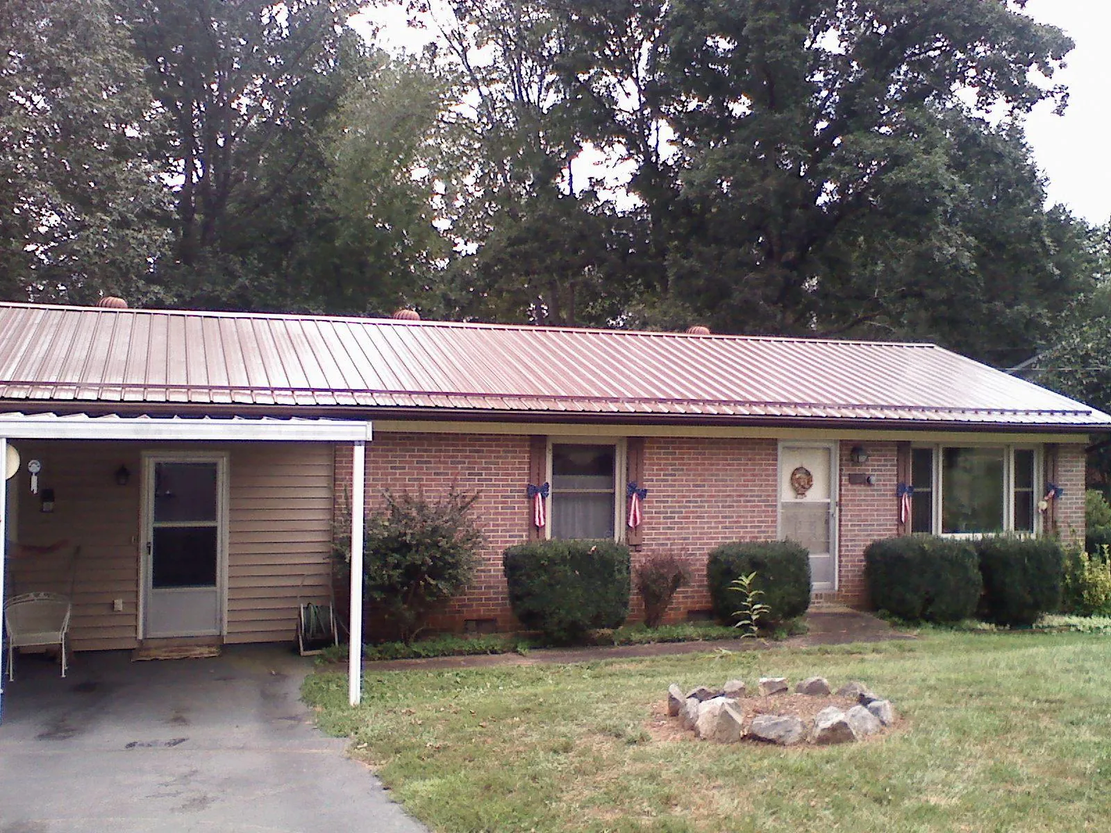 Bronze metal roof and carport on a brick ranch home — Roof Repair work by our crew in Lusk