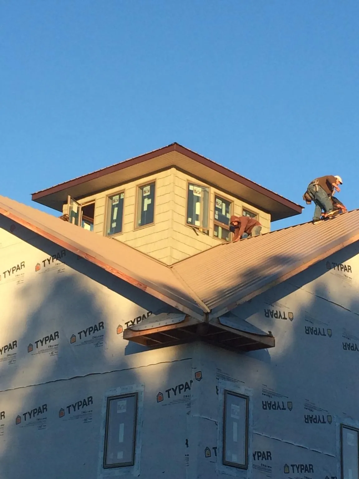 Roofers working around a rooftop cupola on a new metal roof at sunset — Roof Waterproofing in Lusk by Roofing Brothers